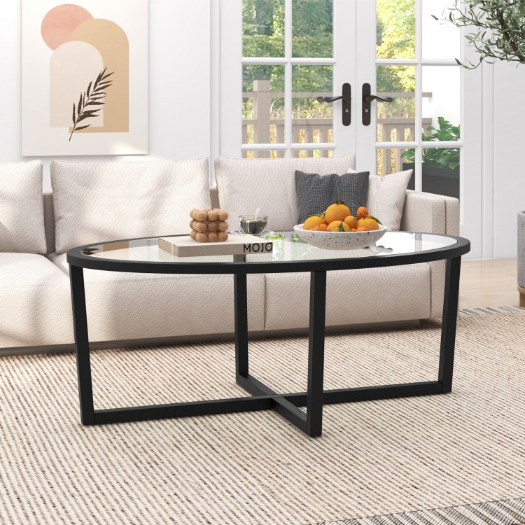 Oval glass coffee table with black cross base and acacia wood legs, perfect for living room decor and stability.