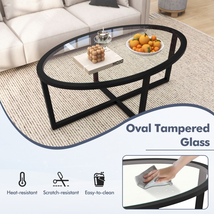 Oval tempered glass coffee table with black acacia wood legs, featuring a cross base for stability and easy cleaning.