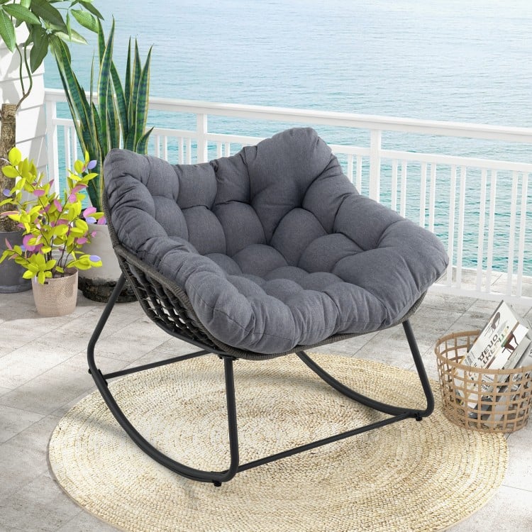 Oversized gray outdoor rocking chair with thick cushion and PE wicker, perfect for relaxing on the patio or balcony.