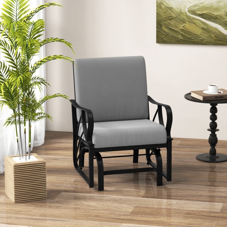 Patio glider rocking chair in gray with thick cushion and curved armrests, perfect for outdoor relaxation.