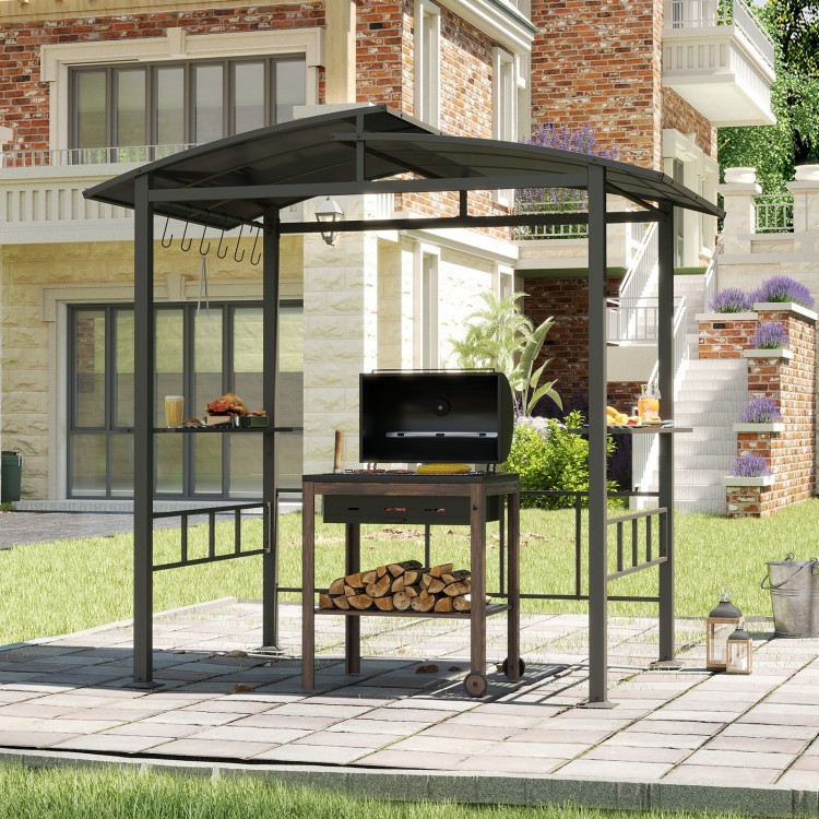 Hardtop grill gazebo with vented polycarbonate roof, black frame, and side shelves for outdoor cooking preparation.