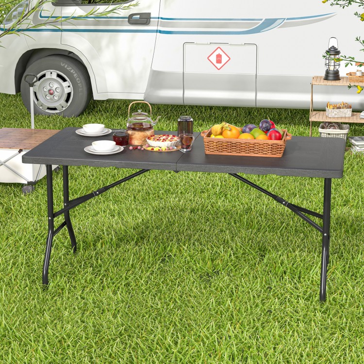 5FT folding picnic table with wood grain HDPE tabletop, set outdoors with food and drinks for versatile gatherings.