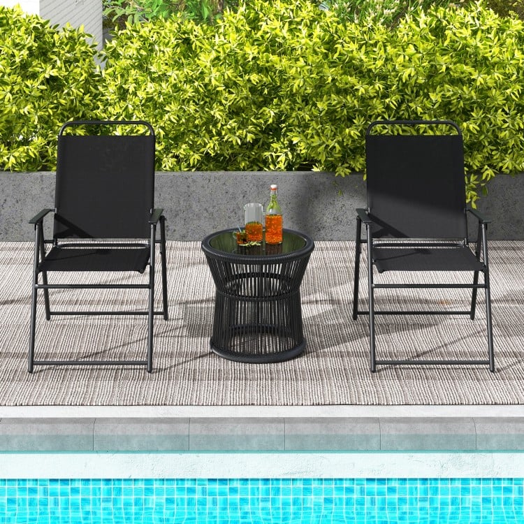 Black outdoor folding sling chairs with armrests and a side table, perfect for poolside relaxation.