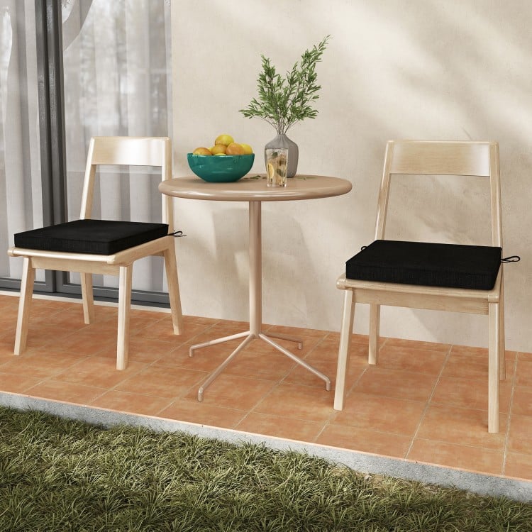 Black outdoor chair cushion set of 2, waterproof and fade-resistant, placed on dining chairs for added comfort.