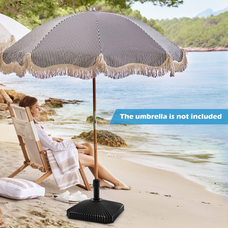 Fillable umbrella base in black with shell texture, designed for 6-10 ft patio umbrellas, shown on a beach setting.