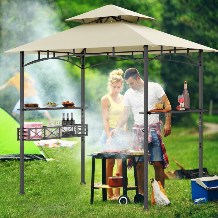 Outdoor grill gazebo with beige canopy, two side shelves, and hooks for tools, perfect for backyard grilling.