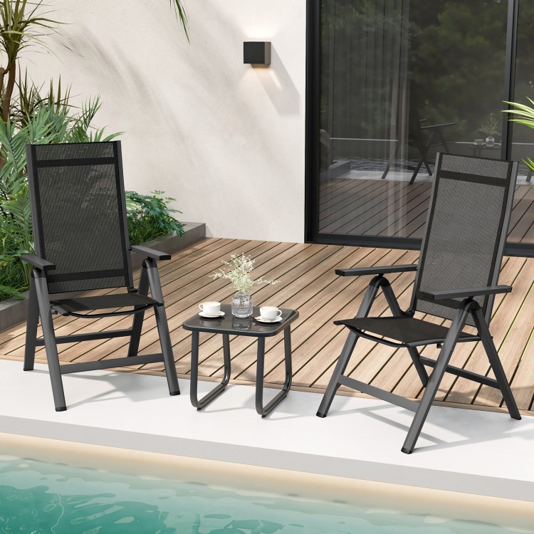 Two black outdoor dining chairs with padded seats and adjustable backrests, set on a wooden deck by the pool.