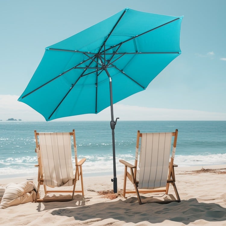 10 ft vented patio umbrella in green with push button tilt, providing shade for two beach chairs by the ocean.