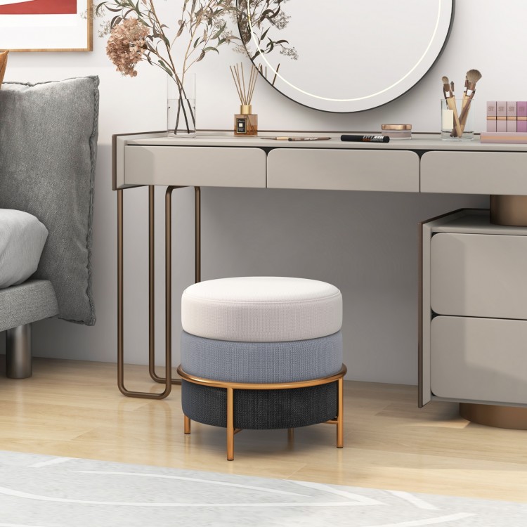 Round upholstered ottoman in gray with gold metal legs, perfect as a footrest or side table for versatile use.