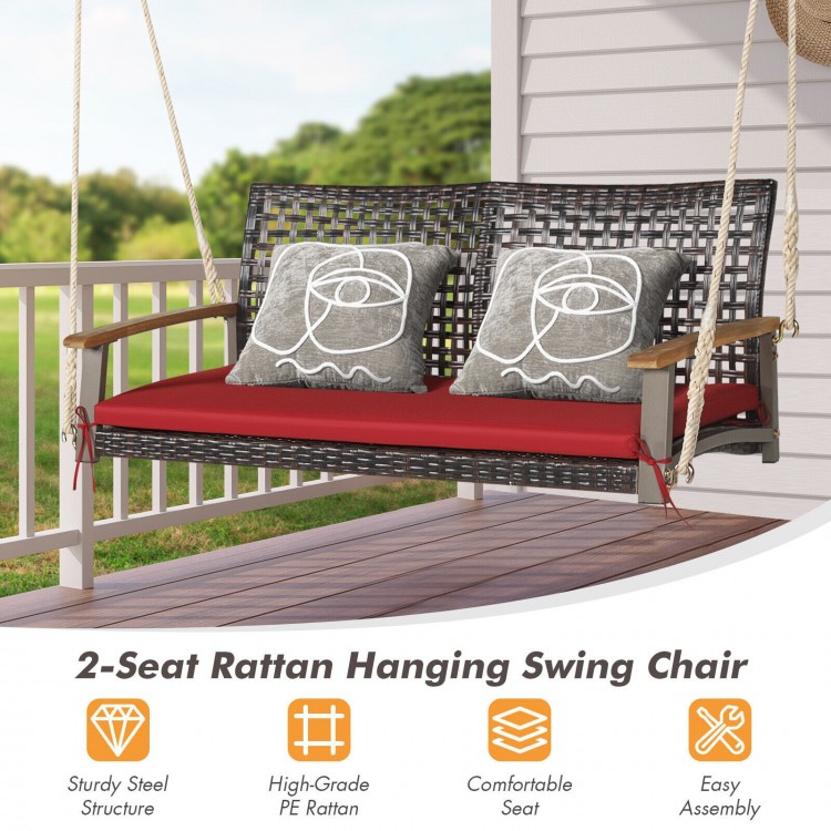 2-seat rattan hanging swing chair with red cushion, sturdy steel frame, and acacia wood armrests for outdoor relaxation.