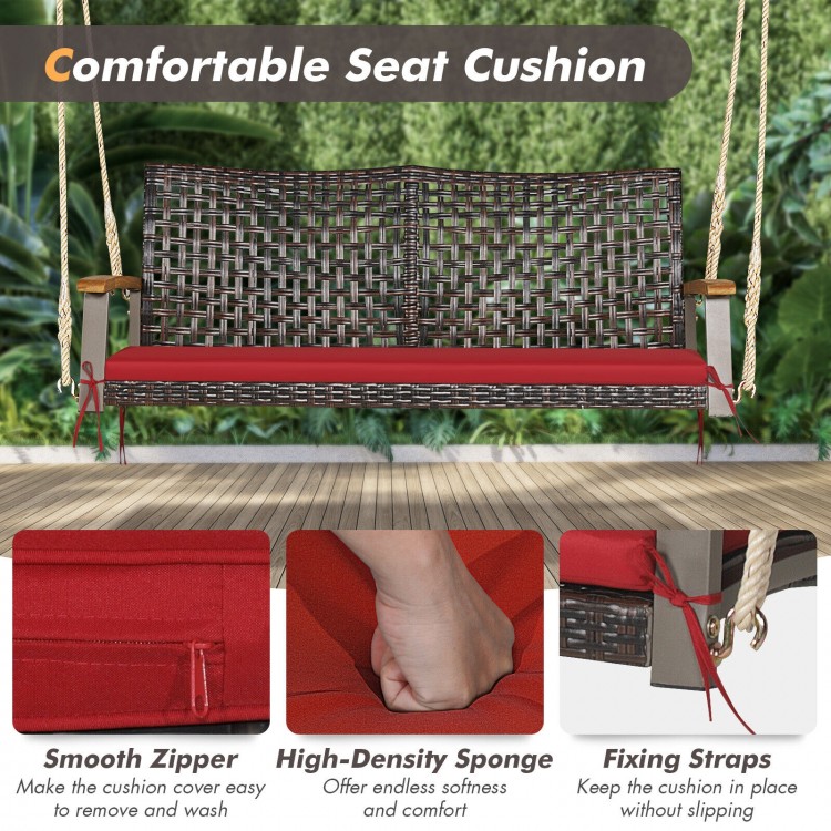 Rattan hanging porch swing chair with red cushion, featuring acacia wood armrests and sturdy steel frame for outdoor.