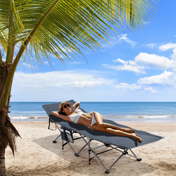 Folding retractable camping cot in blue with soft mattress, set up on the beach for outdoor relaxation.