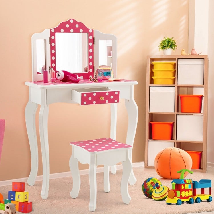 Kids vanity table and stool set in pink with polka dot print, featuring a tri-fold mirror and ample storage for.