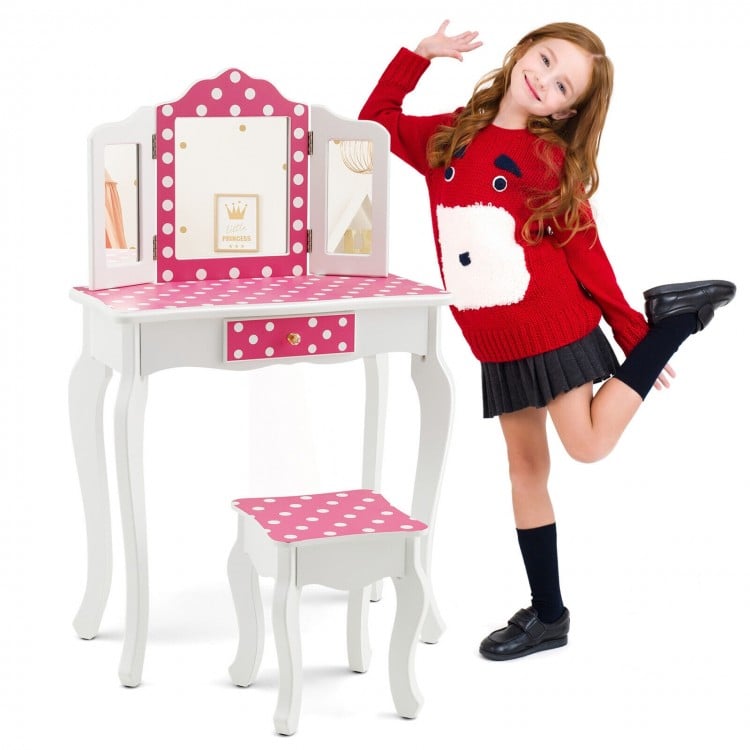Kids vanity table and stool set in pink with polka dot print, showcasing a child posing playfully beside the stylish.