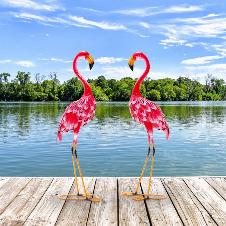 Two pink metal flamingo garden statues with U-shaped stakes, perfect for charming backyard or lakeside decoration.