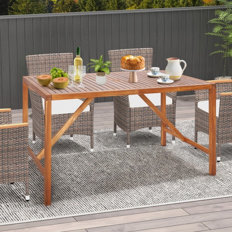67-inch acacia wood dining table with umbrella hole, ideal for outdoor gatherings, shown with decorative items.