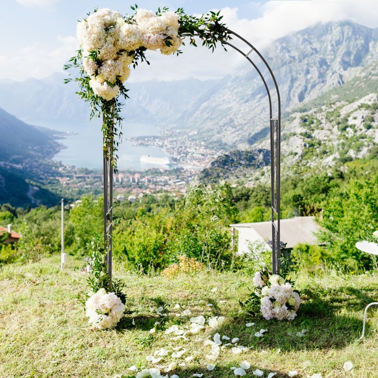 Garden arch trellis in black metal with floral decorations, ideal for outdoor events and climbing plants.