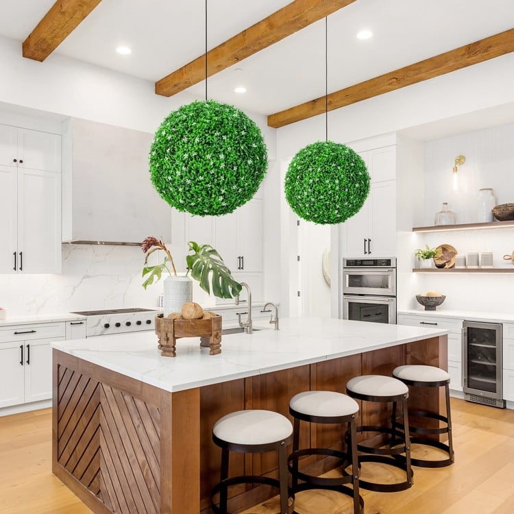 Two 19.5-inch faux boxwood topiary balls in a modern kitchen setting, adding vibrant greenery to the space.