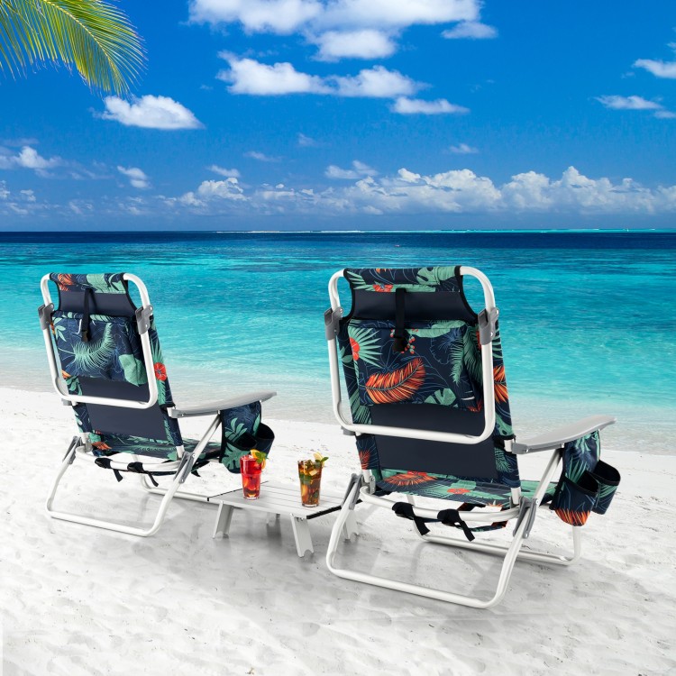 Two reclining beach chairs with tropical design and a side table, perfect for outdoor relaxation by the sea.