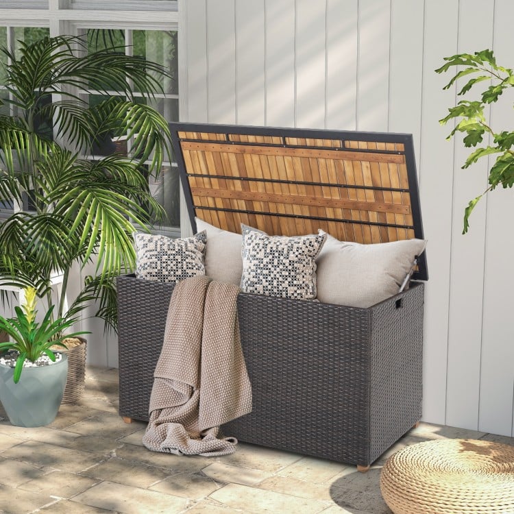 Rattan storage box with solid acacia wood top, featuring a zippered liner, perfect for patio or backyard use.