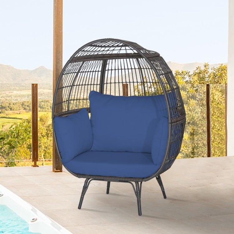 Oversized patio rattan egg lounge chair with navy cushions, featuring a sturdy frame and cozy design for outdoor.