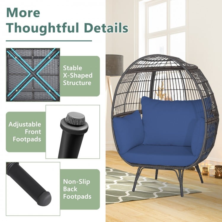 Oversized patio rattan egg lounge chair with navy cushions, featuring adjustable footpads and sturdy X-shaped structure.