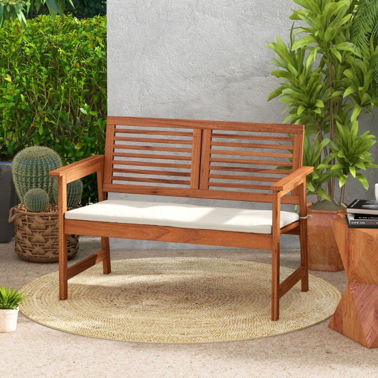 Solid wood patio bench with backrest and cushion, designed for two, perfect for backyard relaxation.