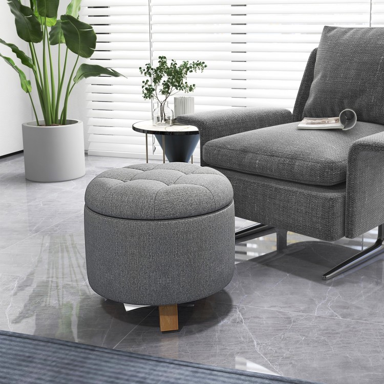 Round gray upholstered ottoman with solid rubber feet, featuring storage space and cushioned seat for versatile use.