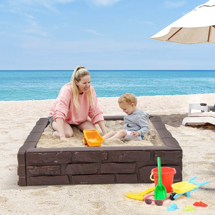 Kids playing in the 2-In-1 HDPE brown sandbox with cover, perfect for outdoor fun and creativity by the beach.