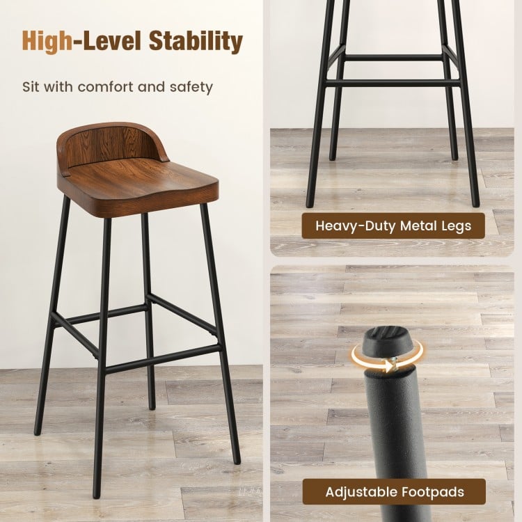 Industrial bar stool with low back, sturdy metal legs, and adjustable footpads for stability in kitchen or dining areas.