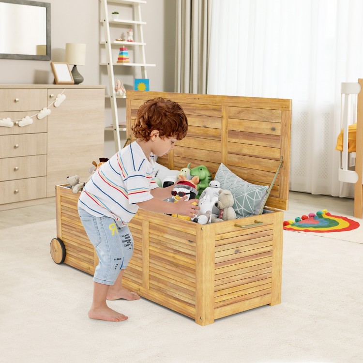 Rolling patio wooden deck box with two wheels, storing toys, made of natural acacia wood for outdoor use.