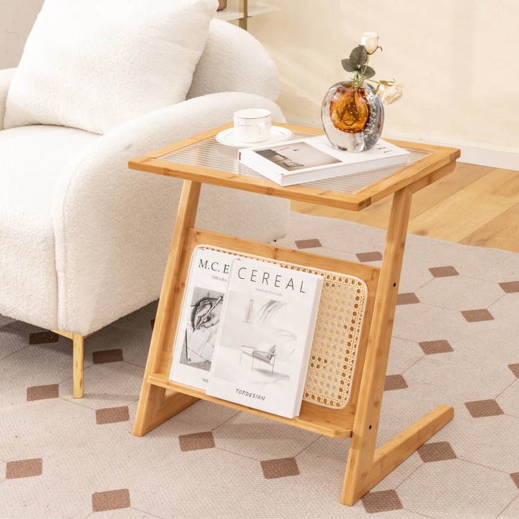 Z-shaped end table with a natural bamboo finish, featuring a rattan shelf and glass top, perfect for narrow spaces.