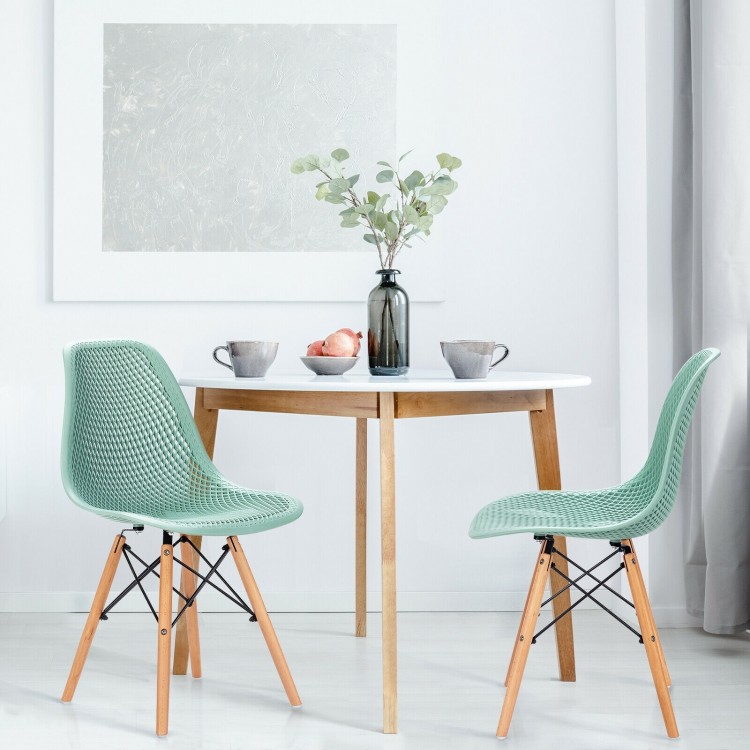 Modern green plastic hollow chair set with wood legs, featuring ergonomic design for dining room comfort.