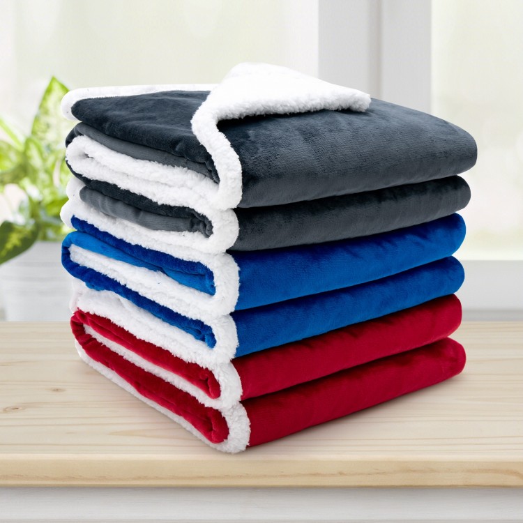 Stack of reversible electric heated blankets in blue, red, and gray flannel and sherpa, ideal for warmth and comfort.