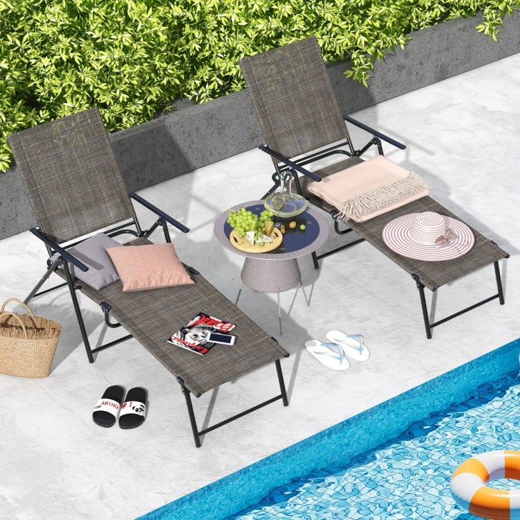 Two adjustable coffee patio folding chaise lounge chairs with a compact design, perfect for poolside relaxation.