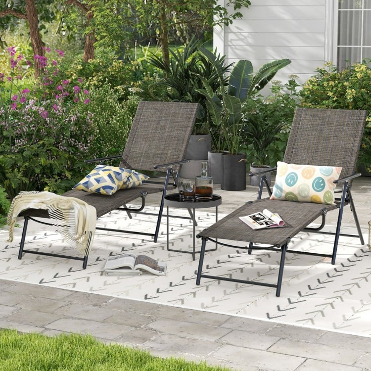 Two coffee-colored folding chaise lounge chairs with adjustable backrests, perfect for backyard relaxation.