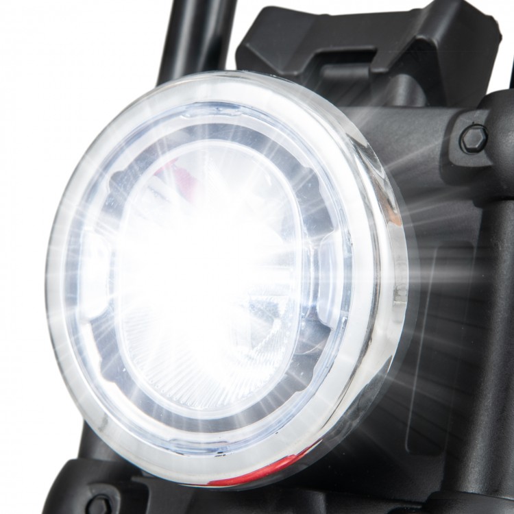 Close-up of the bright LED headlight on a red kids electric motorcycle with training wheels for safe riding.