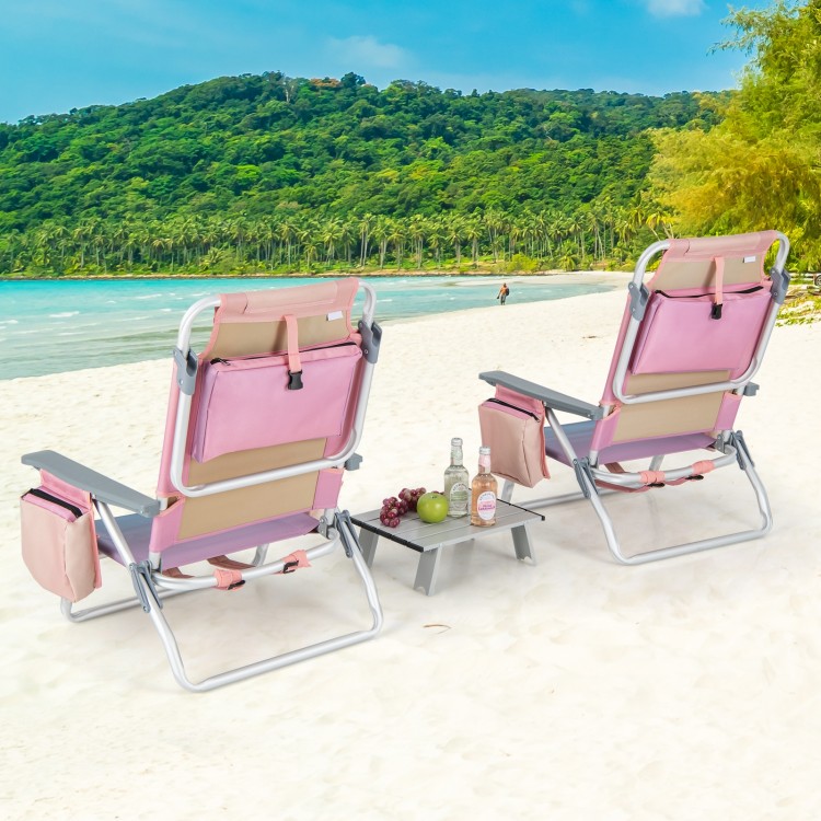 Two pink reclining beach chairs with a folding side table, perfect for outdoor relaxation by the water.