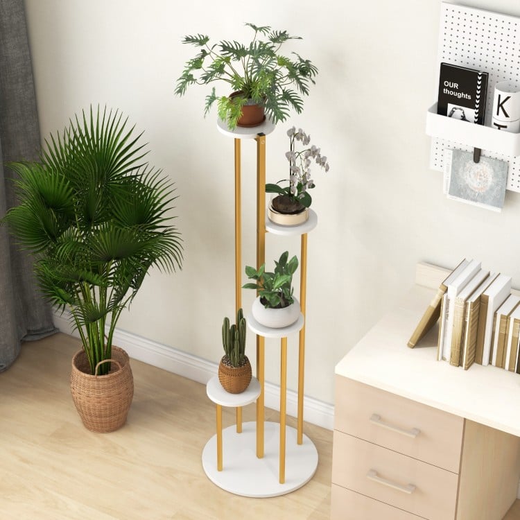 Indoor metal plant stand featuring a golden frame and white shelves, showcasing potted plants in a compact design.