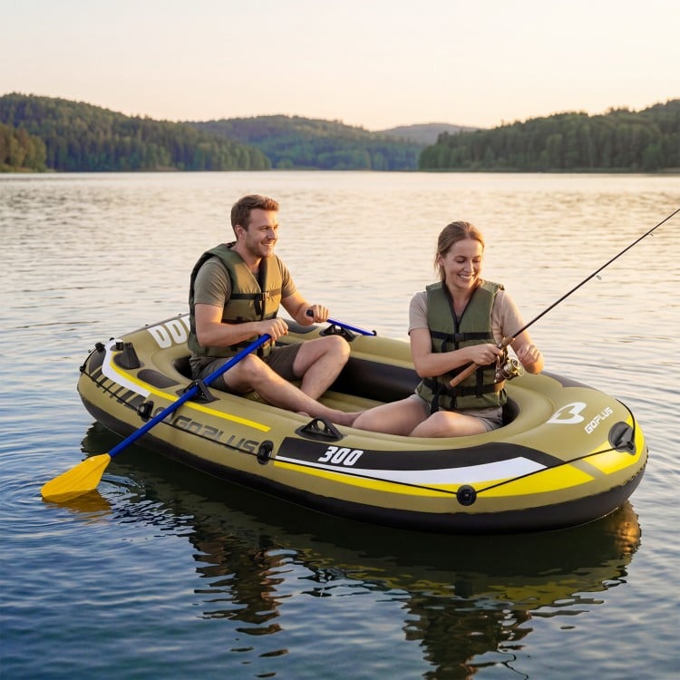 Three-person inflatable fishing raft in green, featuring oars and pump, perfect for lakeside adventures.
