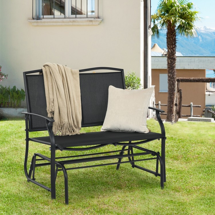Black iron patio rocking chair with a cozy blanket and pillow, perfect for leisurely afternoons in the backyard.
