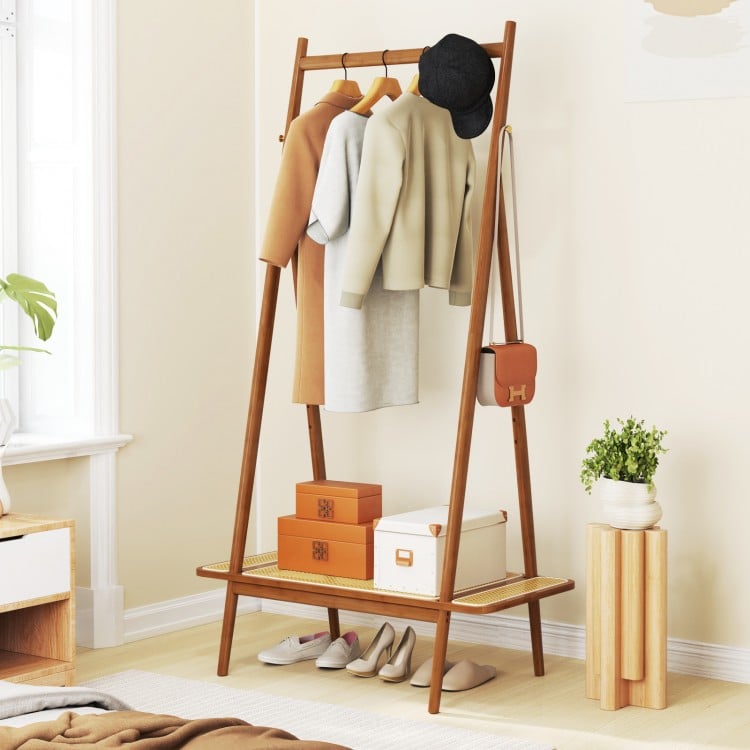 Bamboo clothes rack with a spacious rattan shelf and copper hooks, providing versatile storage for clothes and.