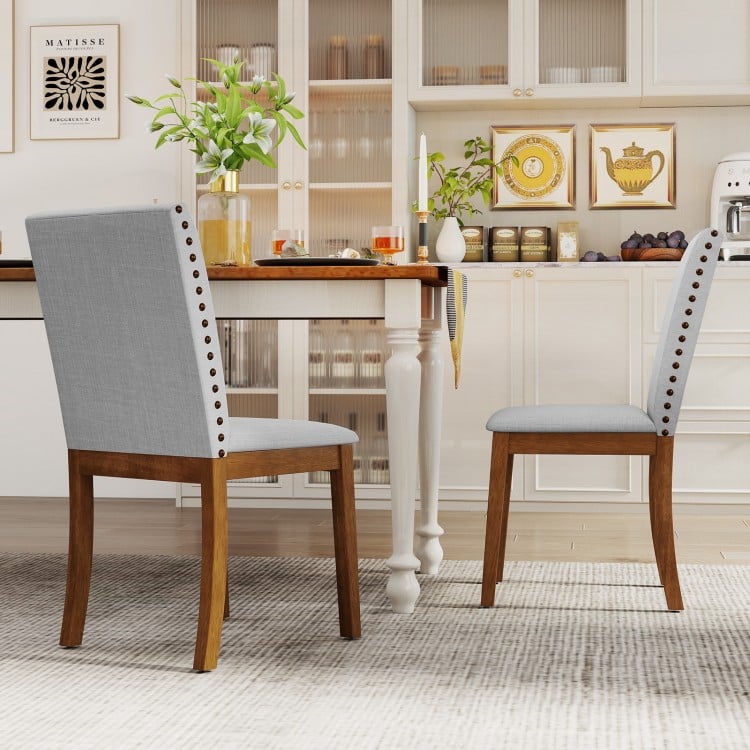 Upholstered dining chairs with padded seats and walnut legs, featuring decorative nailhead trim for elegant dining.