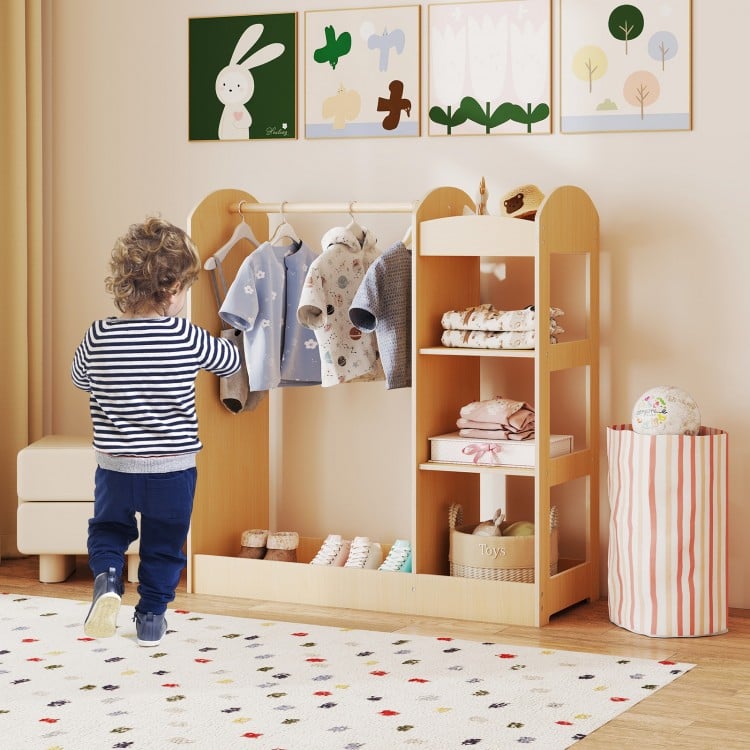 Kids dress-up storage with mirror in natural wood, featuring clothes hanger and open shelves for organized playroom use.