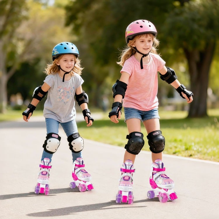 Two girls roller skating in the park wearing adjustable rose red roller skates with light-up wheels and protective gear.