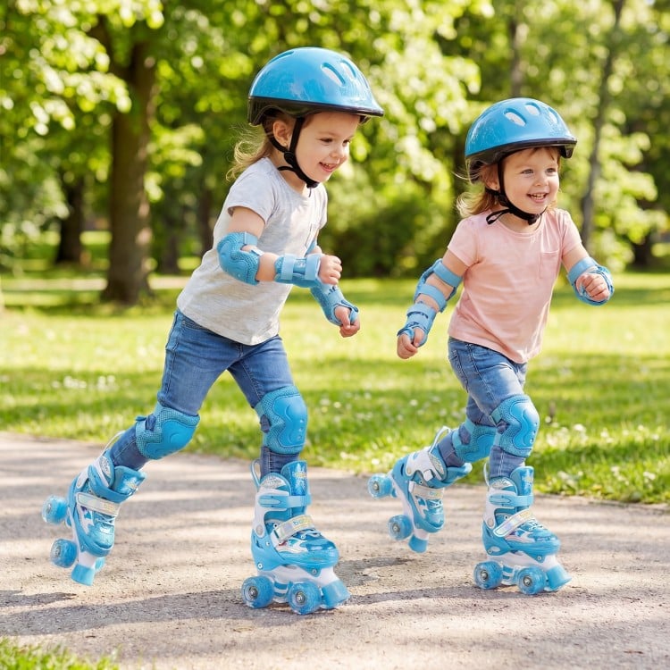 Two kids wearing blue adjustable roller skates with light-up wheels, enjoying a fun day outdoors in a park.