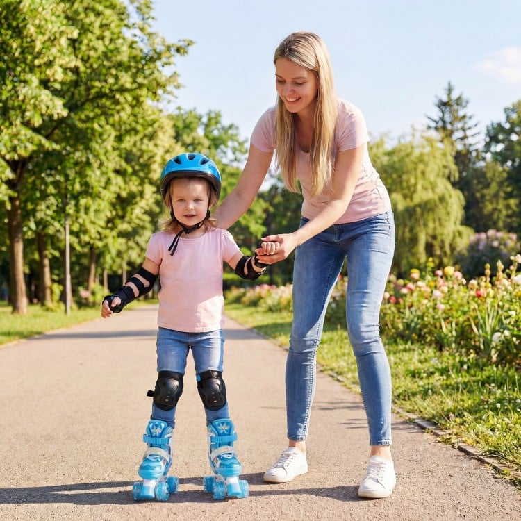Child wearing blue adjustable roller skates with light-up wheels, assisted by an adult in a park setting.