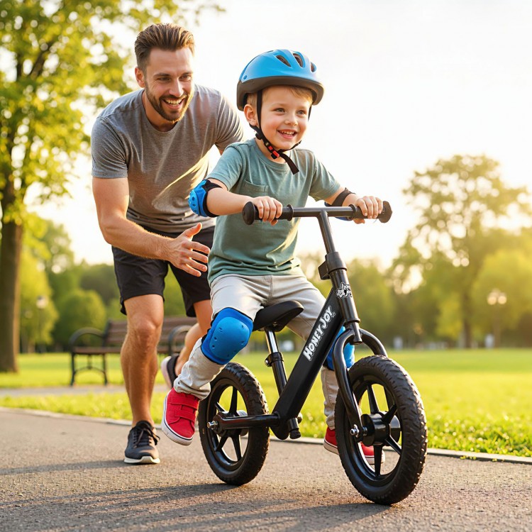 Toddler riding a lightweight black balance bike with adjustable seat and anti-skid tires, enjoying outdoor fun.