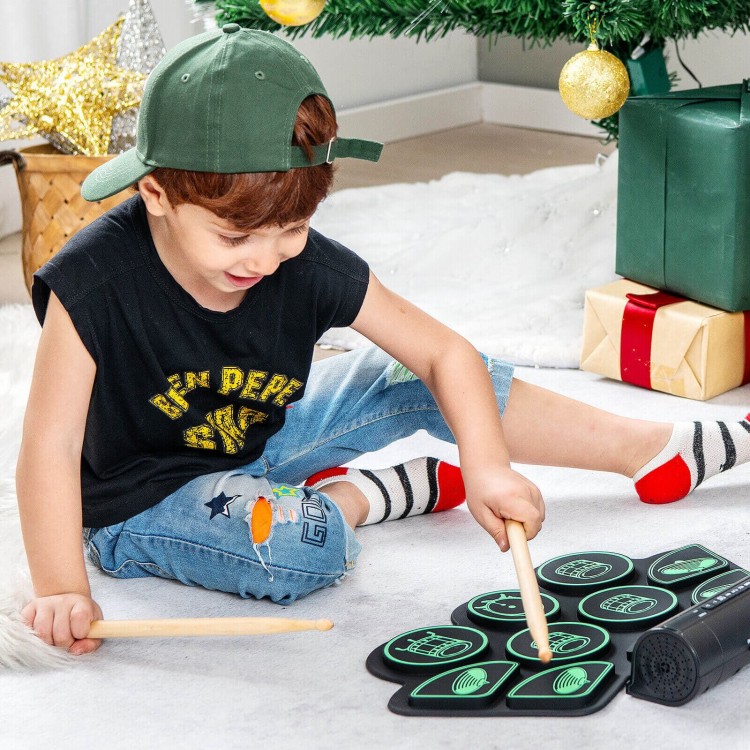 Child playing with the green electronic drum set, featuring built-in stereo speakers and various sound options for fun.