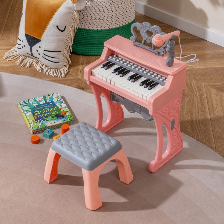 Mini keyboard piano for kids in pink with 25 keys, matching stool, and microphone, perfect for toddlers' music play.